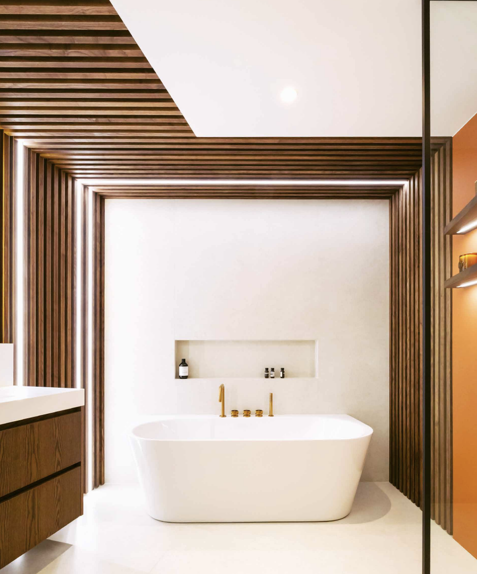 Vue d'une baignoire ilot blanche intégrée dans une salle de bains encadrée par des claustras en chêne pour une perspective lumineuse.