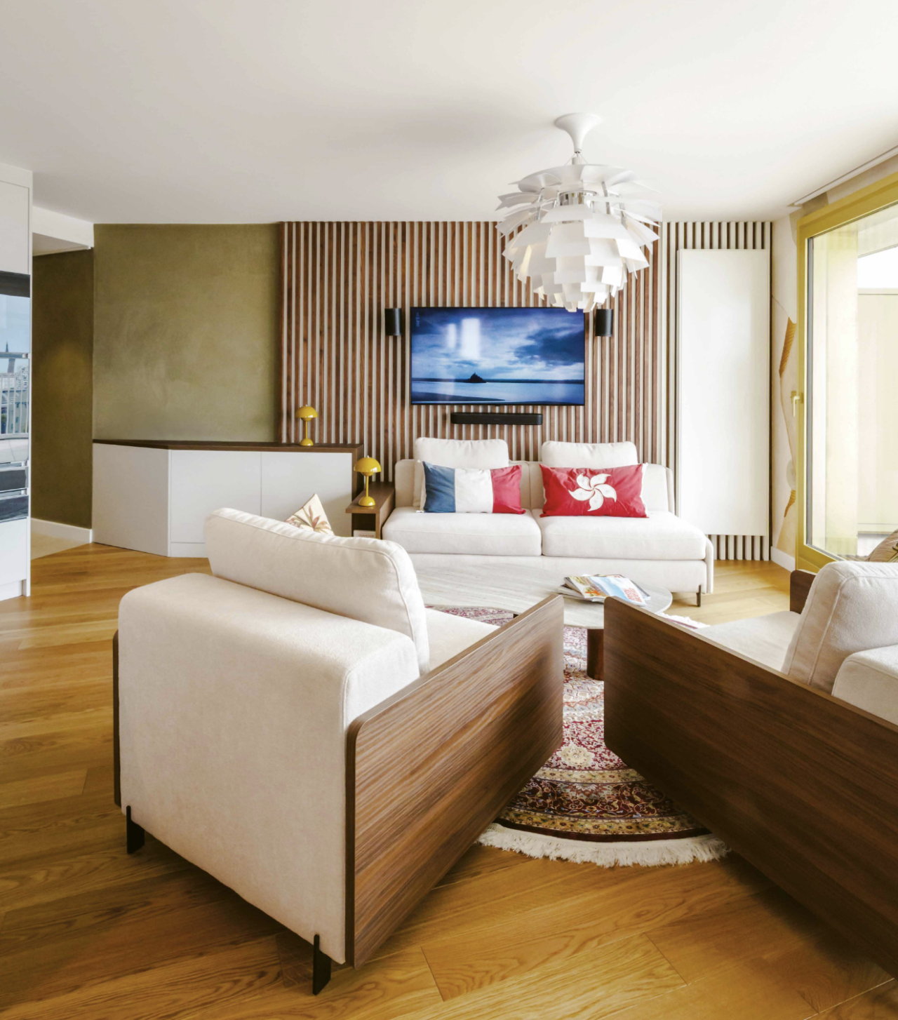 Salon lumineux avec canapés et meuble sur-mesure entouré de panneaux en noyer sur lesquels repose la TV